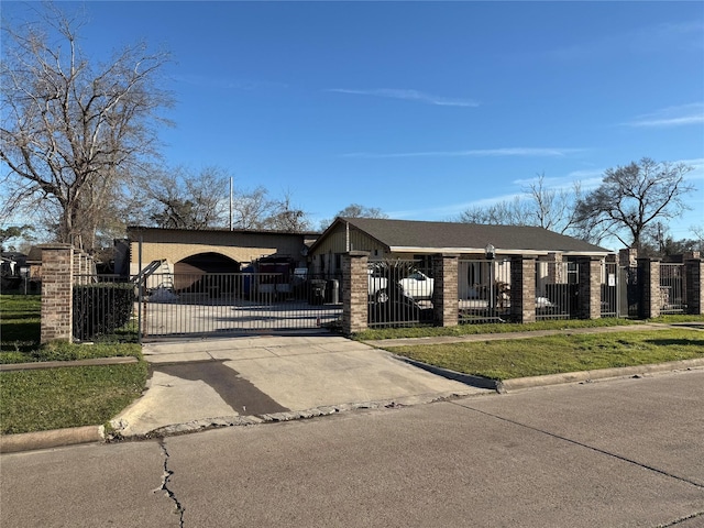 view of front of property with driveway, a fenced front yard, a gate, and brick siding