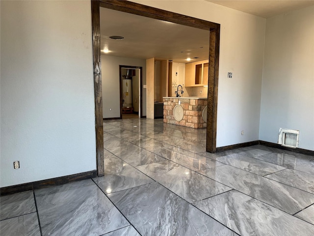 spare room featuring gas water heater, a sink, visible vents, baseboards, and marble finish floor