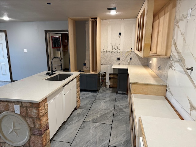 kitchen featuring a sink, marble finish floor, light countertops, tasteful backsplash, and an island with sink