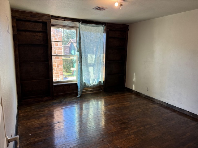 spare room featuring visible vents, plenty of natural light, and hardwood / wood-style flooring