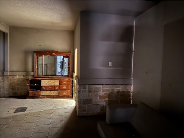 bathroom with a wainscoted wall, vanity, toilet, and a textured ceiling