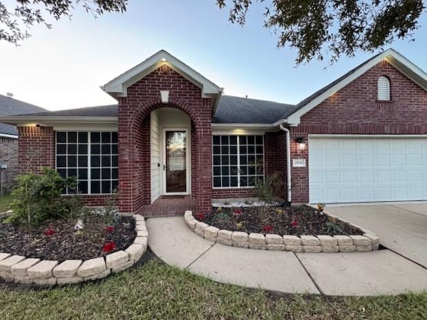 ranch-style house featuring a garage, brick siding, and driveway