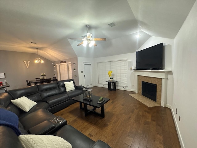 living area with visible vents, vaulted ceiling, ceiling fan with notable chandelier, a tile fireplace, and wood finished floors