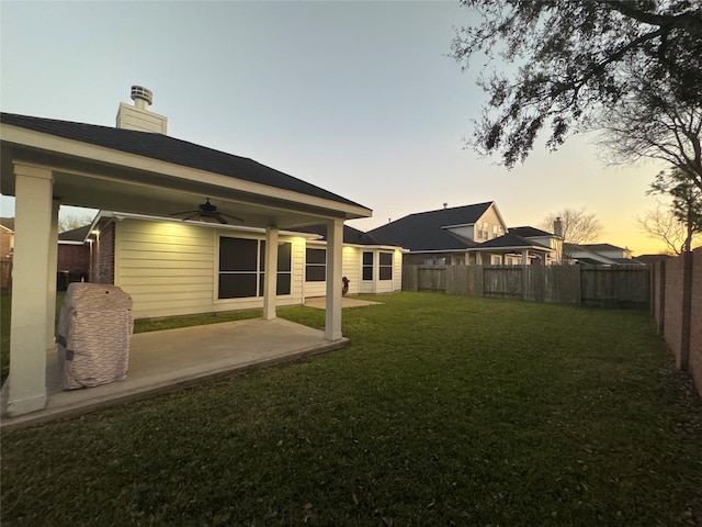 view of yard with a fenced backyard, ceiling fan, and a patio area