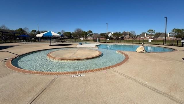 community pool with a patio area and fence