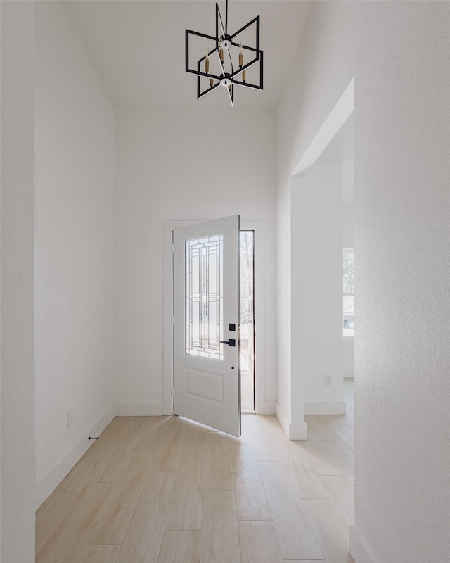 foyer with an inviting chandelier, wood finished floors, and baseboards