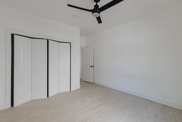 unfurnished bedroom with a closet, ceiling fan, light wood-style flooring, and baseboards