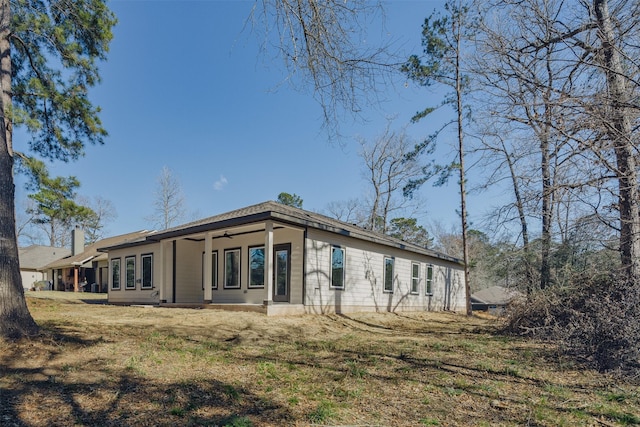 rear view of property with a yard and a ceiling fan