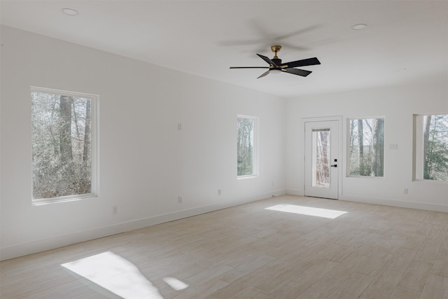 spare room featuring light wood finished floors, ceiling fan, and baseboards