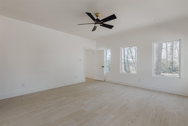 spare room with baseboards, a ceiling fan, and light wood-style floors