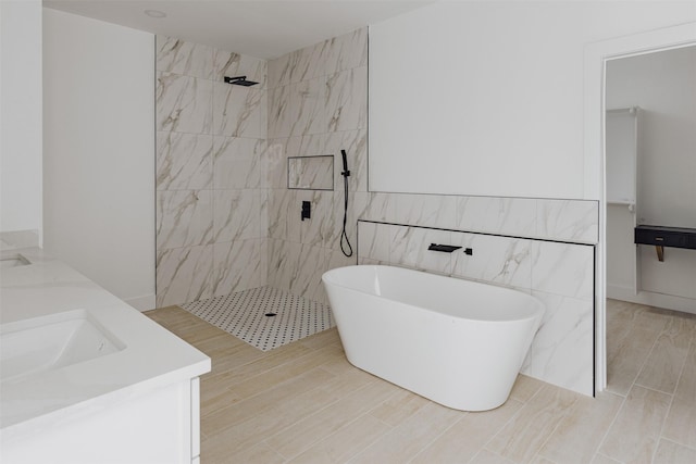 bathroom featuring double vanity, tile walls, walk in shower, and a freestanding bath