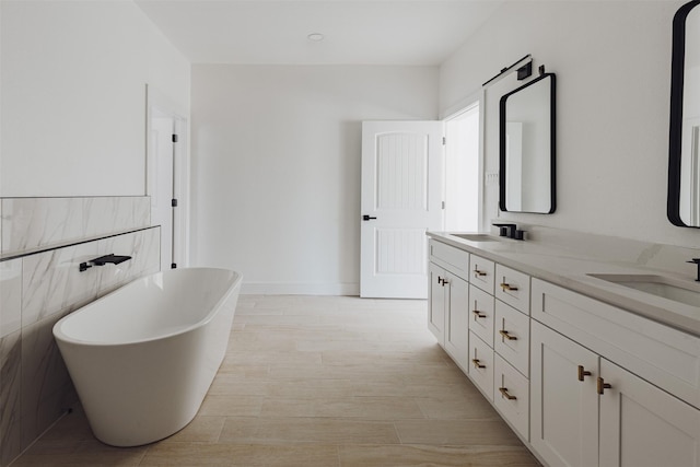 full bathroom featuring a freestanding bath, double vanity, a sink, and tile walls