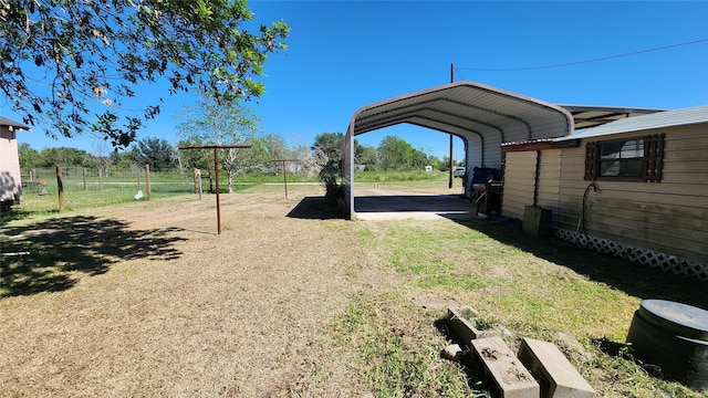 view of yard with driveway, fence, and a detached carport