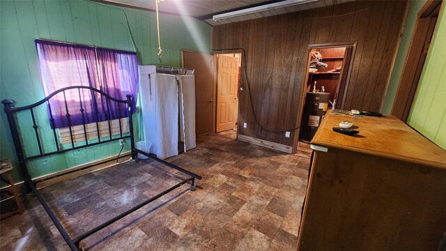 bedroom with water heater, stone finish flooring, and wood walls