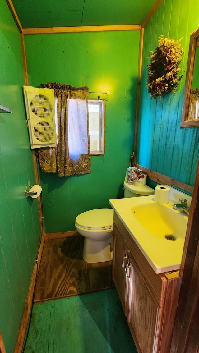 half bath with wooden walls, vanity, and toilet