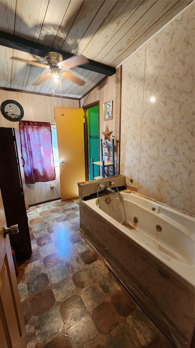 bathroom featuring wood ceiling, a ceiling fan, beam ceiling, a whirlpool tub, and stone finish flooring