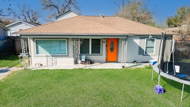 view of front of property featuring a trampoline, a front yard, a shingled roof, and fence