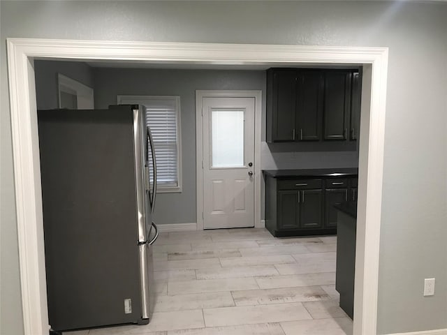 kitchen with baseboards, dark countertops, freestanding refrigerator, and light wood-style floors