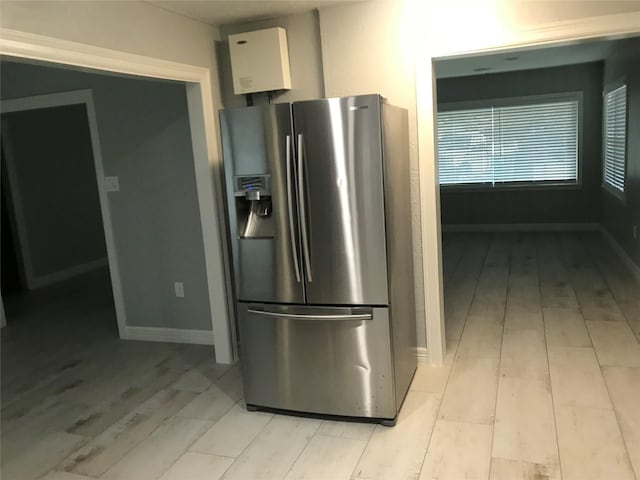 kitchen featuring light wood-style floors, baseboards, white cabinets, and stainless steel fridge with ice dispenser