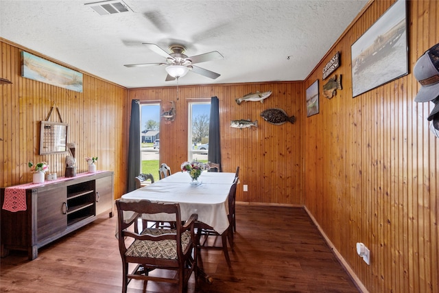 dining space with baseboards, a textured ceiling, visible vents, and wood finished floors