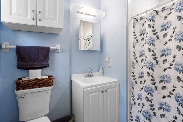 bathroom with a textured wall, a shower with shower curtain, vanity, and toilet