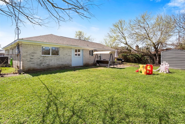 back of house featuring brick siding, a lawn, fence, and a patio