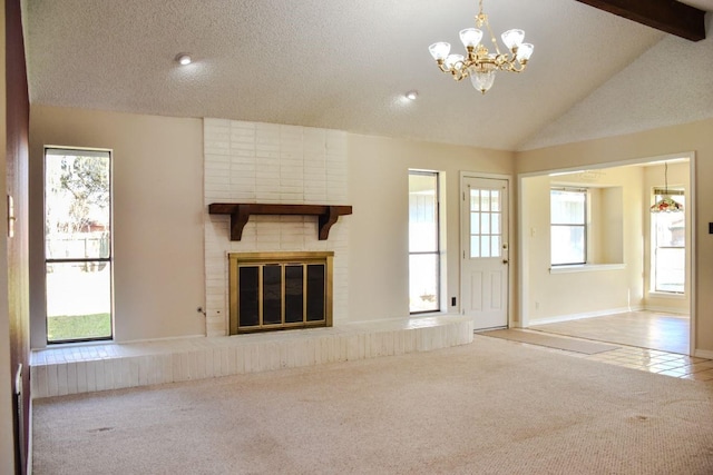 unfurnished living room with lofted ceiling with beams, a textured ceiling, carpet flooring, a brick fireplace, and a chandelier