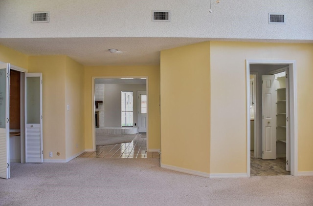 corridor featuring carpet flooring, visible vents, and a textured ceiling