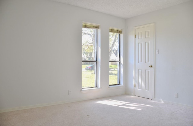 spare room featuring carpet floors, baseboards, and a textured ceiling