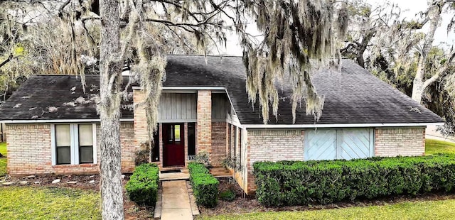 view of front of house with a shingled roof and brick siding