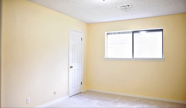 unfurnished room featuring light colored carpet, visible vents, a textured ceiling, and baseboards