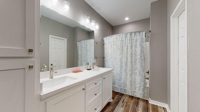 bathroom featuring double vanity, a sink, a shower with shower curtain, and wood finished floors