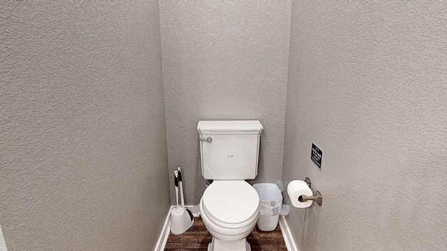 bathroom featuring a textured wall, wood finished floors, toilet, and baseboards