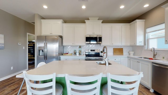 kitchen featuring appliances with stainless steel finishes, white cabinets, a sink, and decorative backsplash