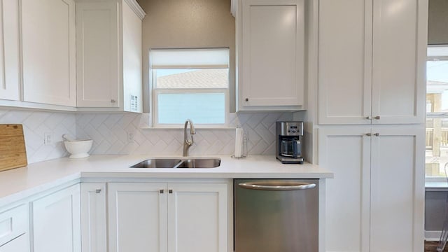 kitchen featuring stainless steel dishwasher, tasteful backsplash, light countertops, and a sink