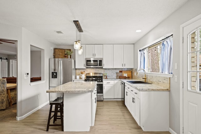 kitchen with stainless steel appliances, tasteful backsplash, a sink, and a barn door