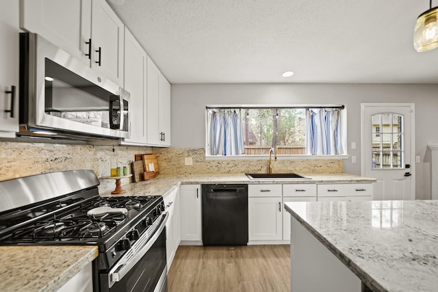 kitchen featuring tasteful backsplash, light wood-style flooring, appliances with stainless steel finishes, white cabinetry, and a sink