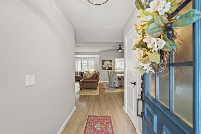 entrance foyer with light wood-style flooring, baseboards, and a textured ceiling