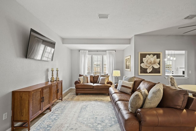 living room featuring baseboards, visible vents, and a textured ceiling