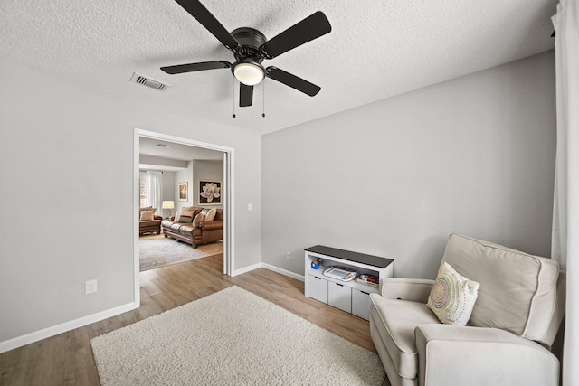 living area featuring wood finished floors, visible vents, and baseboards