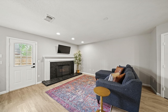 living room with recessed lighting, wood finished floors, visible vents, baseboards, and a glass covered fireplace