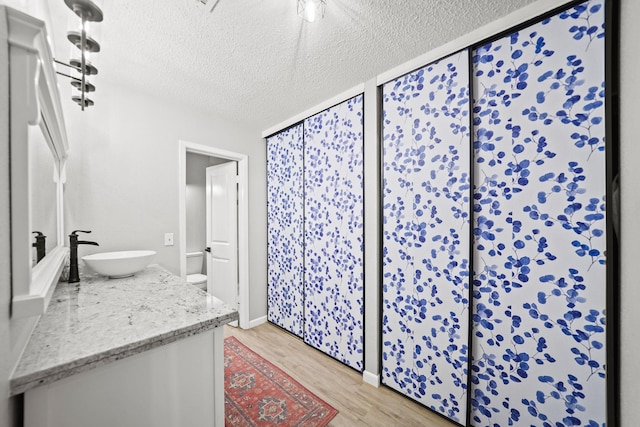 bathroom with vanity, a textured ceiling, toilet, and wood finished floors