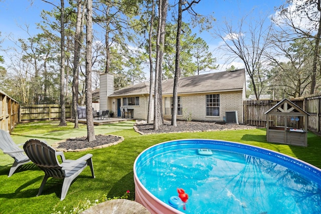 view of swimming pool with a fenced backyard, a yard, a wooden deck, and central air condition unit