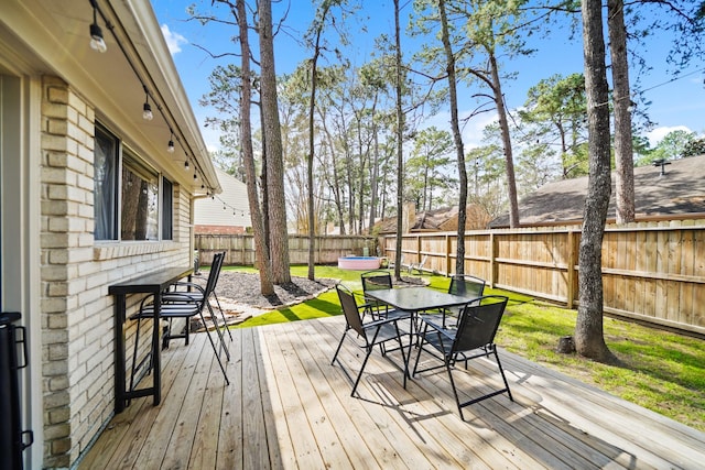 wooden deck with a fenced backyard and outdoor dining area