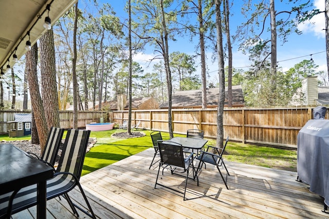 wooden deck with a fenced backyard, a grill, a yard, a swimming pool, and outdoor dining space