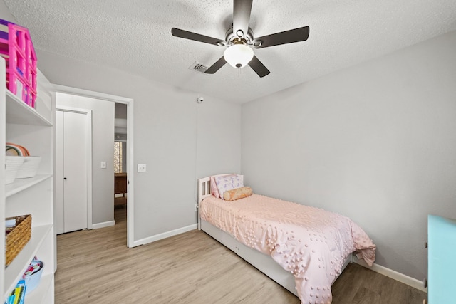 bedroom featuring visible vents, a textured ceiling, baseboards, and wood finished floors