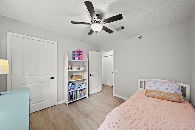 bedroom with baseboards, visible vents, a ceiling fan, wood finished floors, and a textured ceiling