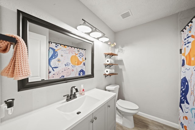 full bathroom featuring visible vents, toilet, a textured ceiling, vanity, and wood finished floors