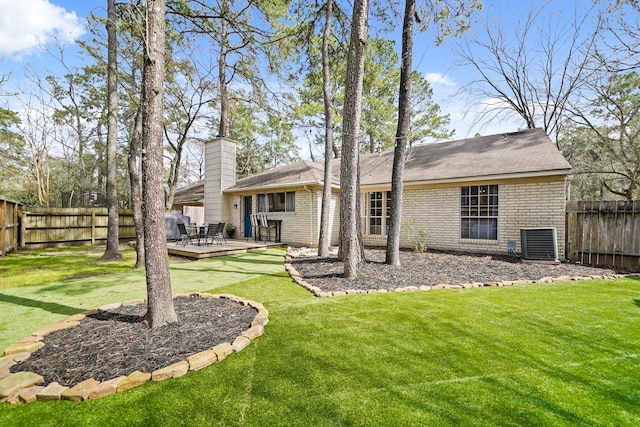 rear view of house featuring a deck, a fenced backyard, central air condition unit, brick siding, and a lawn