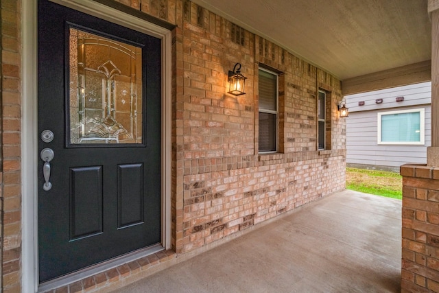 entrance to property featuring covered porch and brick siding